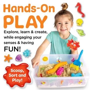 Smiling child playing with beach-themed sensory bin filled with kinetic sand, scoop, molds, and ocean toys for hands-on learning and sensory exploration.